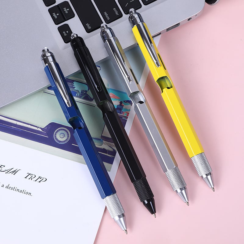 Multitool pens beside a laptop and everyday desk items