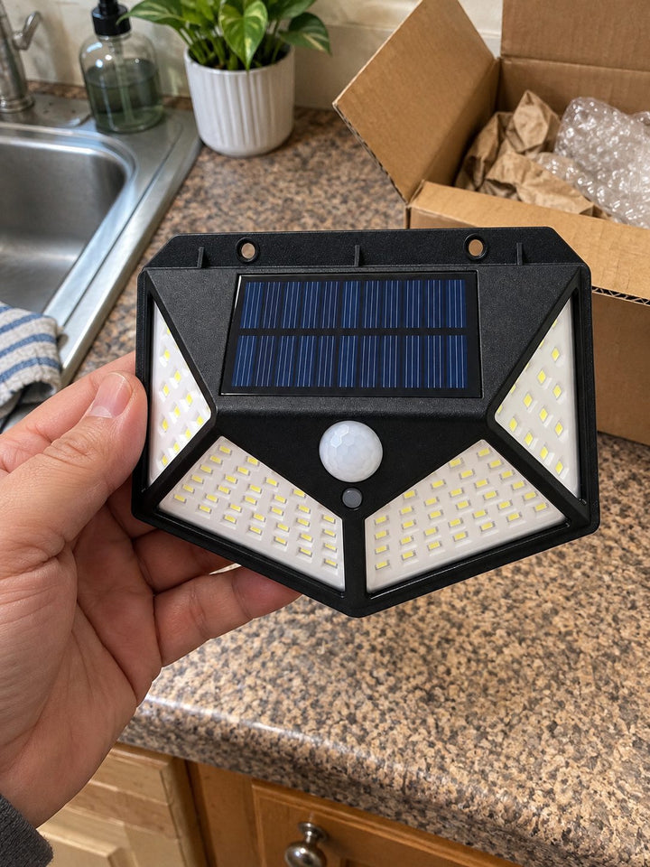 A hand holding the solar wall light beside an open box